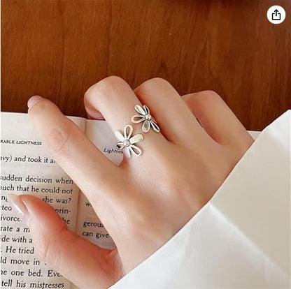 Hand wearing a silver floral ring on a book background