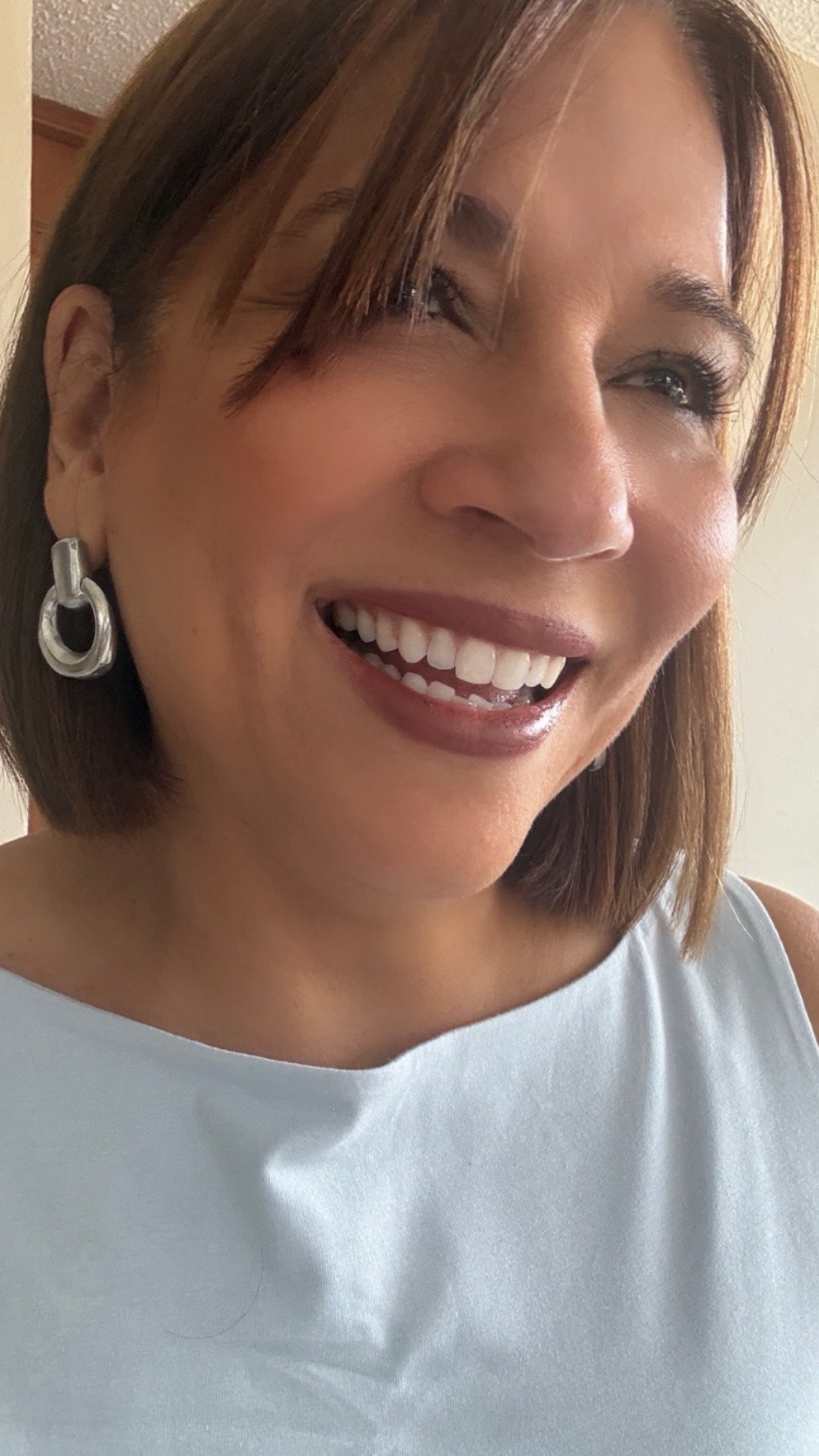 Vestopazzo Oval Round Domed Hoop Earrings – Smiling woman wearing matte silver interlocking hoop earrings with light blue sleeveless top | Místika Style