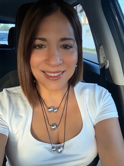 Vestopazzo Three Layers Necklace – Smiling woman wearing triple-strand black cord necklace with silver sphere beads with white top | Místika Style