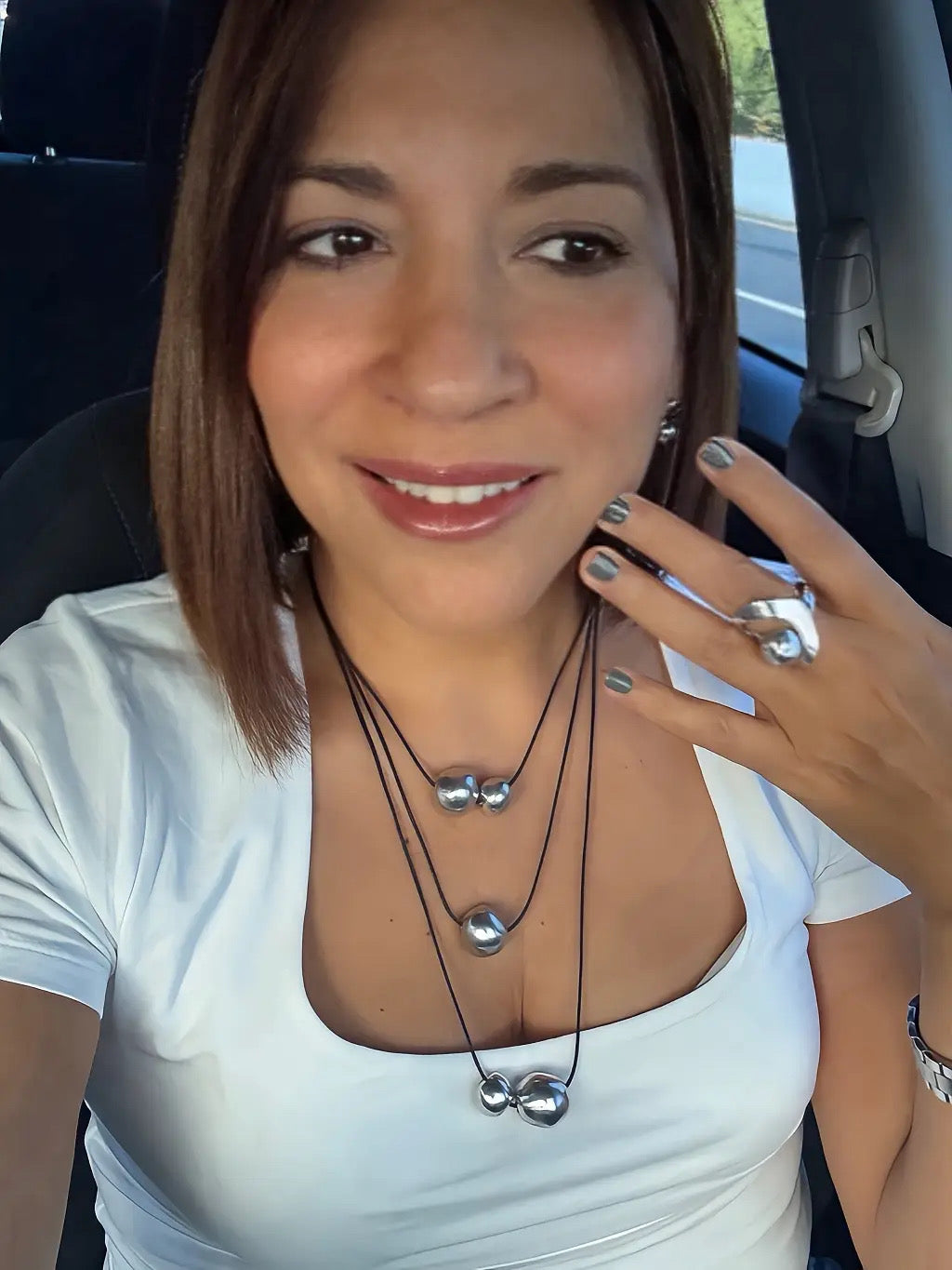 Vestopazzo Three Layers Necklace – Smiling woman wearing triple-strand silver sphere necklace and bold silver ring with white top | Místika Style